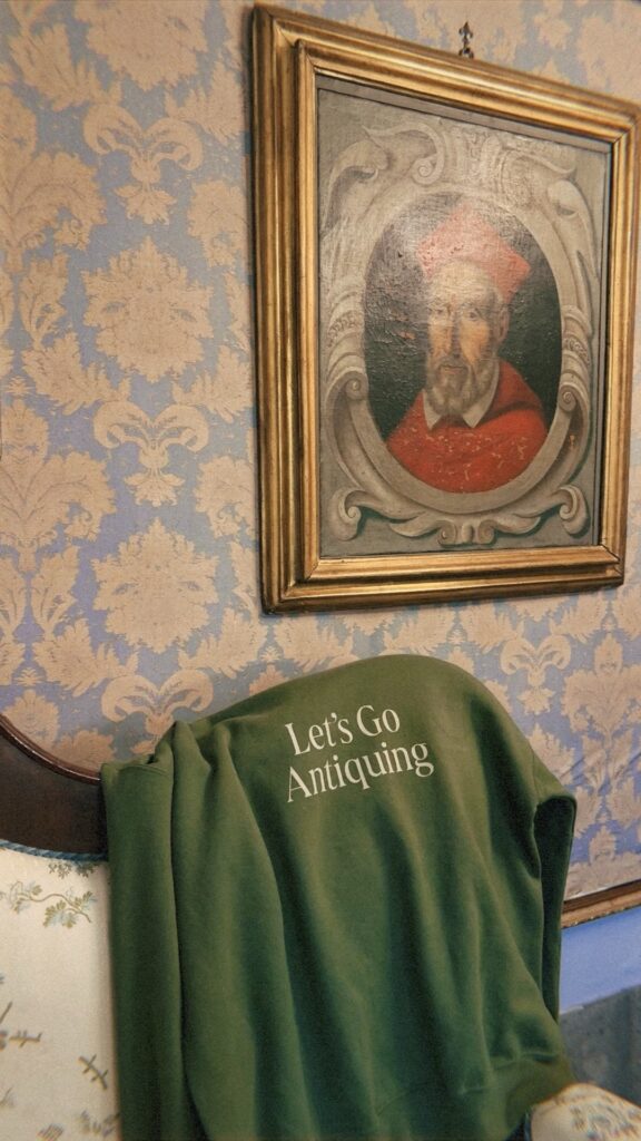 A green sweatshirt with the words "let's go antiquing" lays draped over an antique sofa.